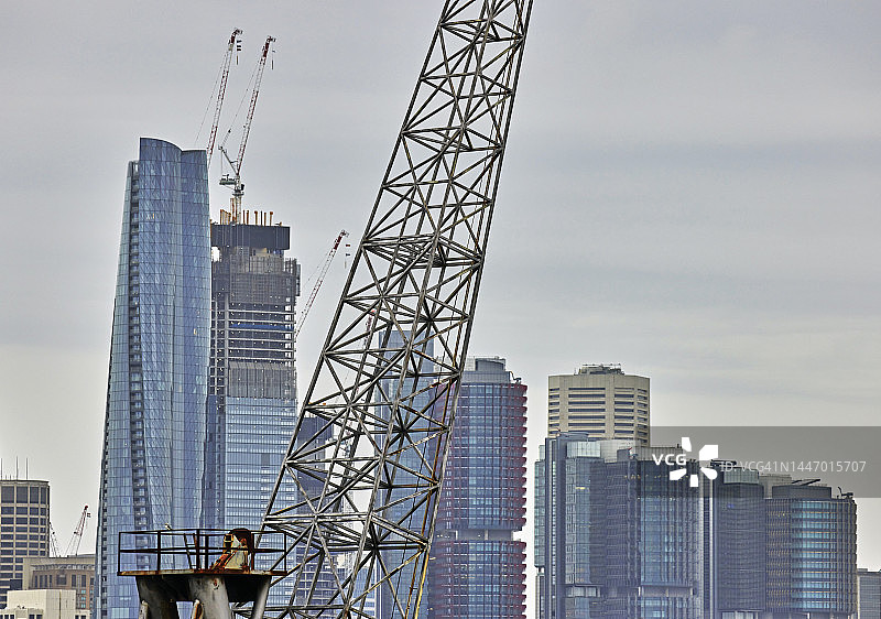 旧金属工业起重机与新的玻璃摩天大楼形成对比图片素材