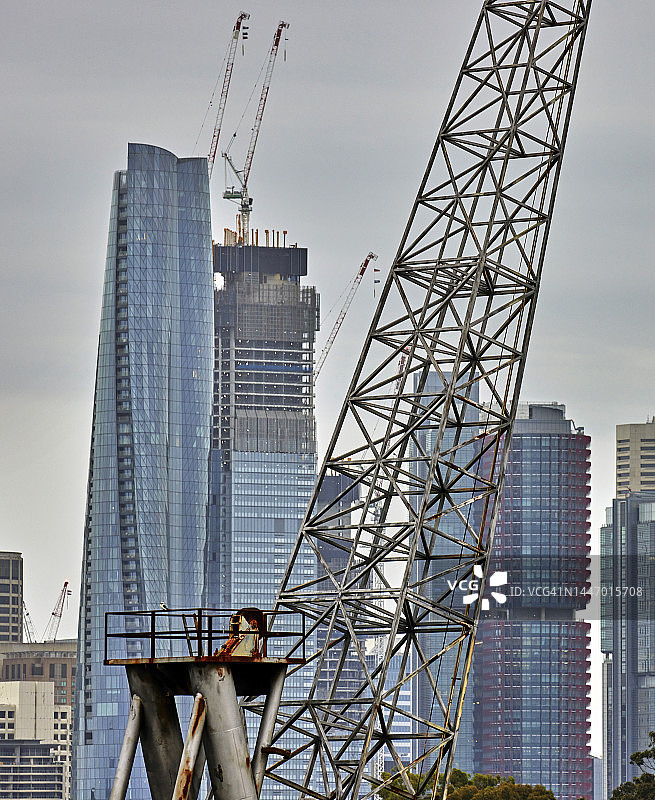 旧金属工业起重机与新的玻璃摩天大楼形成对比图片素材