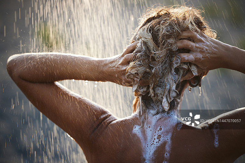 女子在淋浴下洗头发的背影图片素材