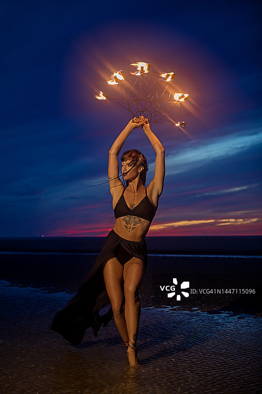 夜晚沙滩上美丽的棕发女火舞者图片素材