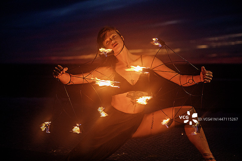 夜晚沙滩上美丽的棕发女火舞者图片素材