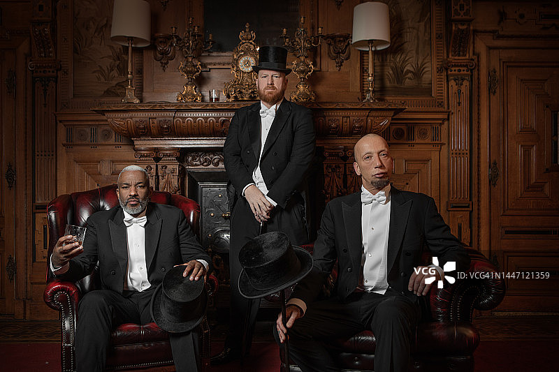 豪华棕色酒吧里的三位英俊的1920年代风格绅士图片素材