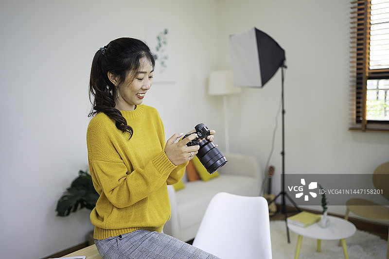 在家中工作室工作的年轻亚洲女摄影师图片素材