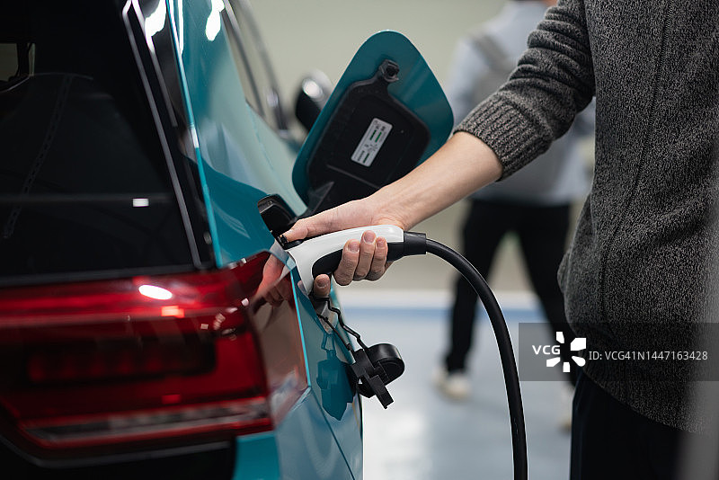 男人给电动汽车充电的特写镜头图片素材