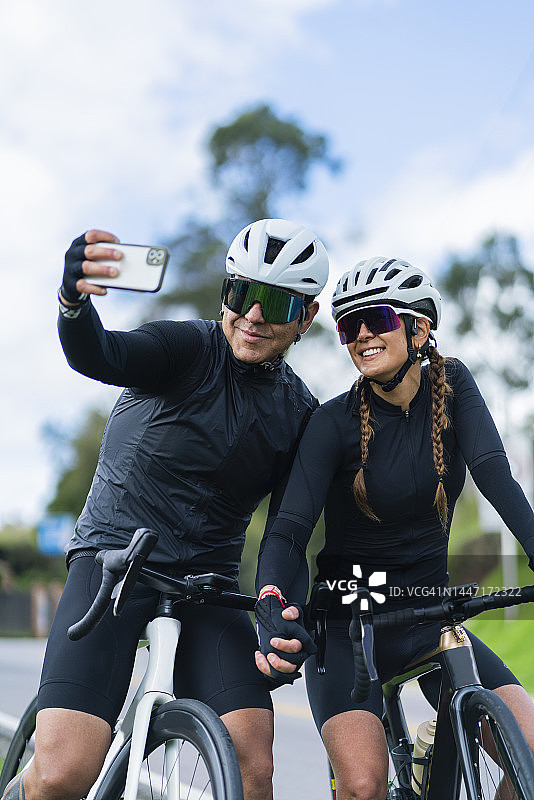 情侣骑着白色自行车在卡希卡-昆迪纳马卡路上行驶，戴着安全头盔和骑行眼镜图片素材