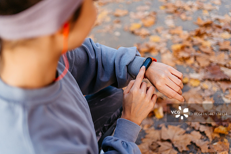 年轻女子在公园慢跑后，在智能手表上查看健身活动图片素材
