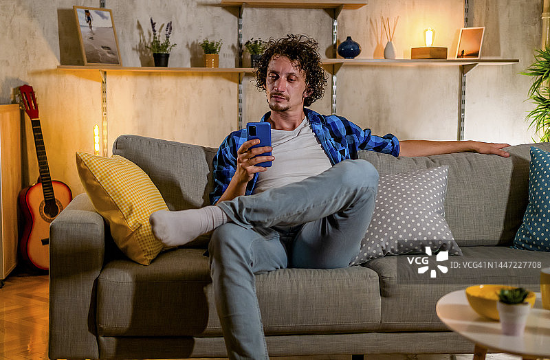 年轻男人在家使用手机图片素材