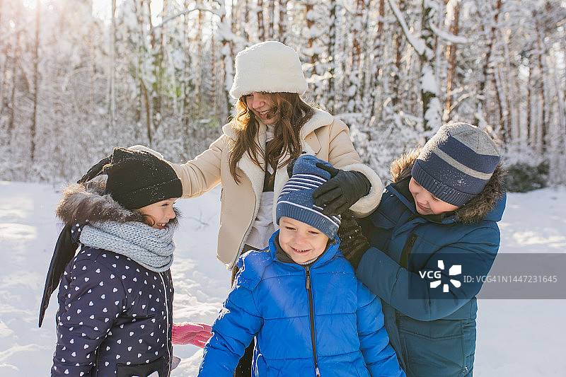 孩子们在冬日森林里玩耍，快乐的童年，冬季假期，厚厚的积雪，男孩和女孩，集体照，暖和的衣服图片素材