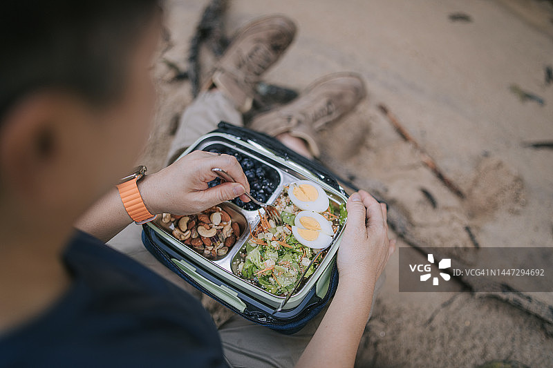 亚裔中年女性在户外享用午餐盒图片素材