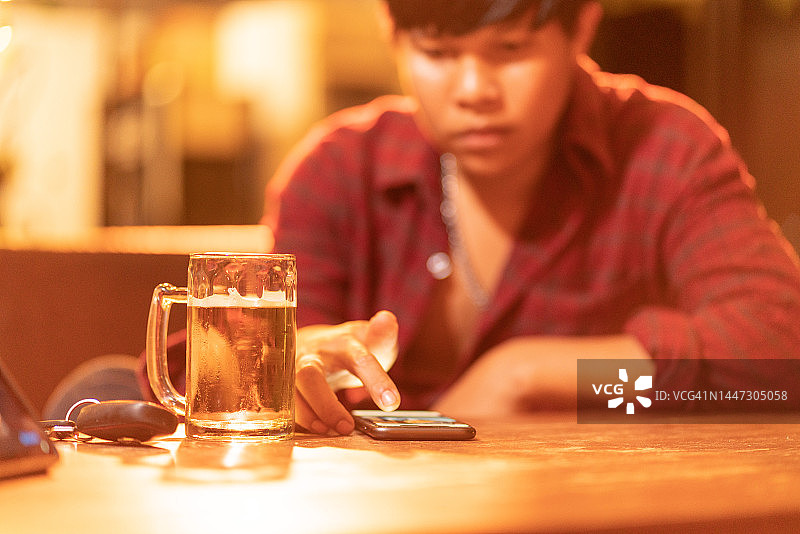 男人在酒吧喝啤酒和使用手机图片素材