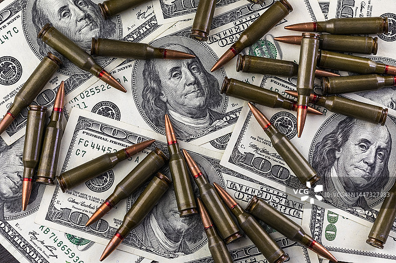 100美元钞票和机枪弹药——战争引发经济危机概念图片素材
