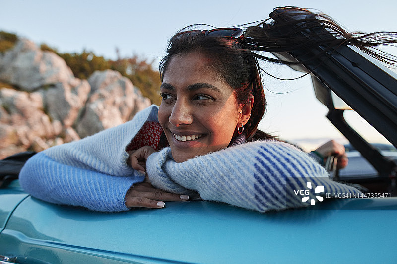 年轻女人在度假时靠在车上图片素材