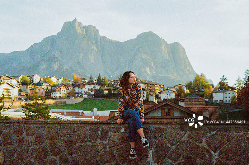 女人坐在多洛米蒂村庄的背景下图片素材