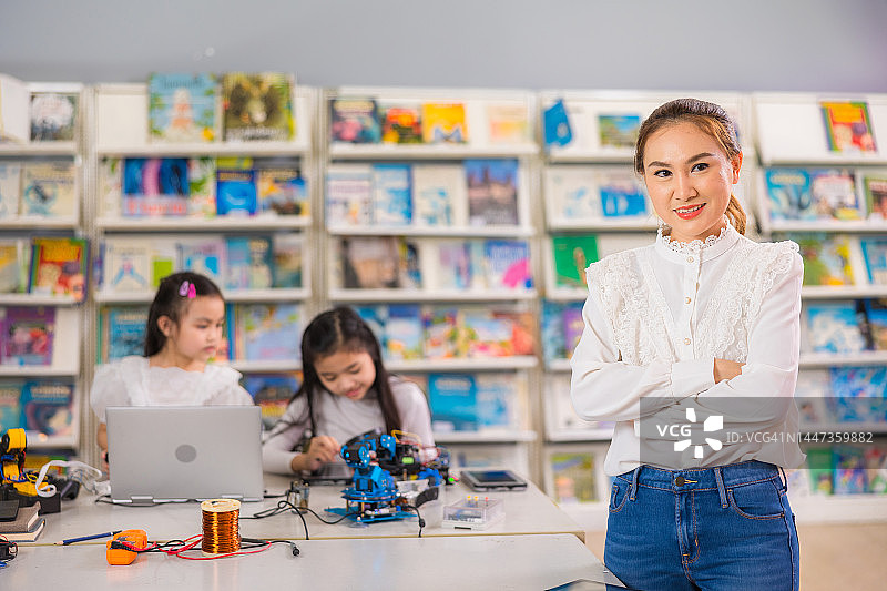 快乐的亚洲女教师站在教室前的肖像图片素材