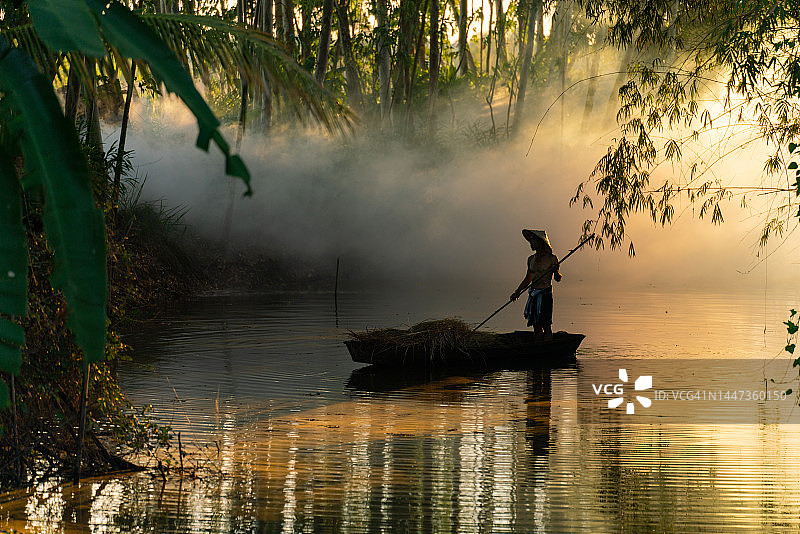 亚洲乡村生活剪影：船夫竹林夕阳下划船运草图片素材