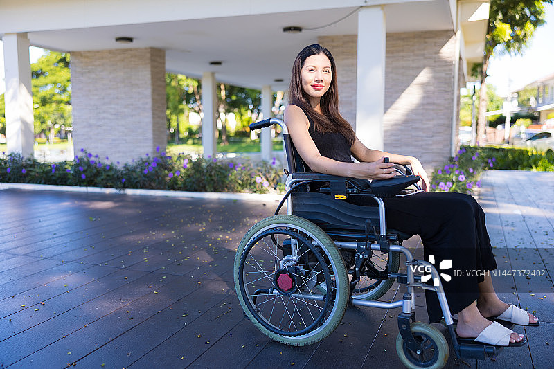 亚洲女性在公园里使用电动轮椅图片素材