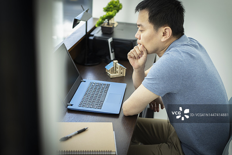 在办公室用笔记本电脑工作的沉思男工程师图片素材