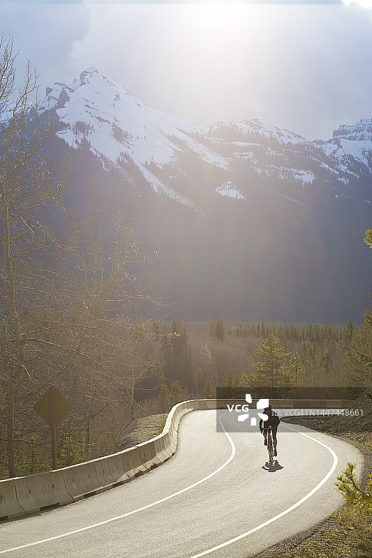女子在班夫国家公园的弓谷公园大道上骑公路自行车图片素材