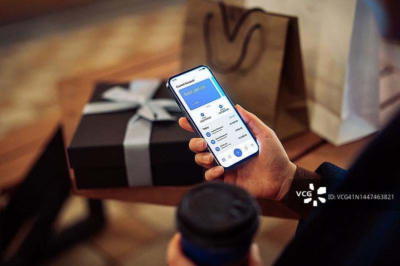 年轻女性在城市购物，使用手机银行App跟踪支出图片素材