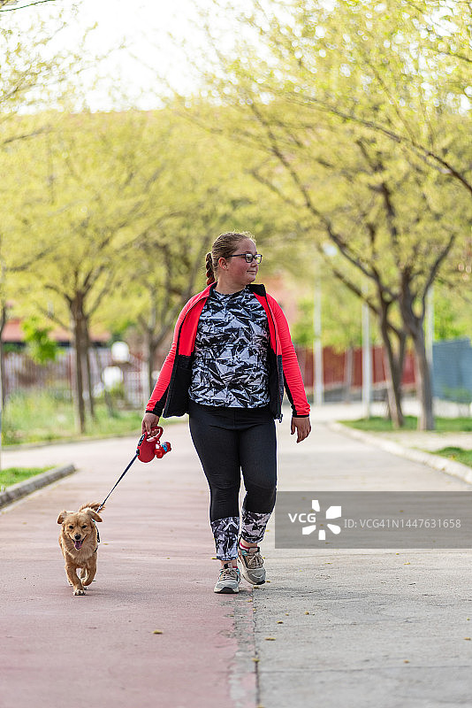 戴眼镜的金发女人在公园遛狗图片素材