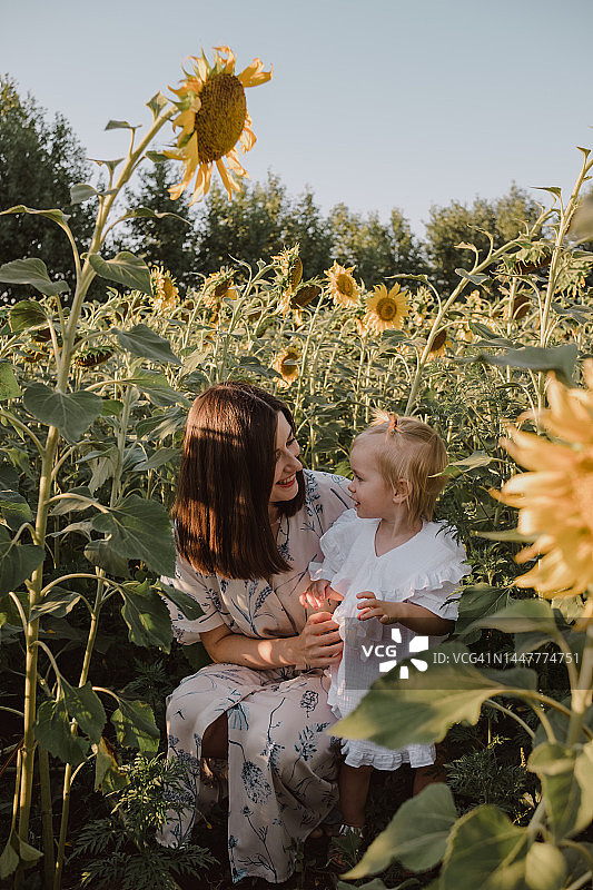 向日葵田中深色头发女孩和儿童的肖像图片素材
