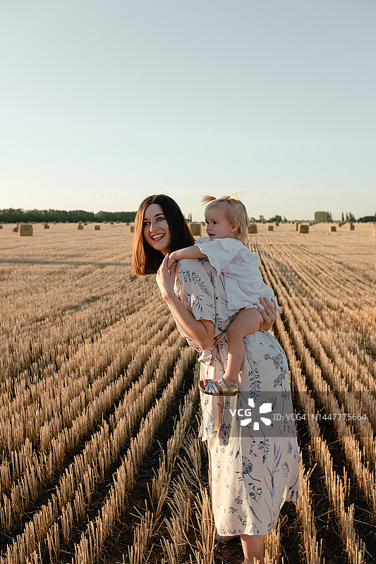 在有干草堆的田野里的母女肖像图片素材