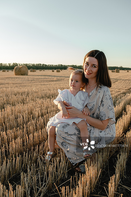 在有干草堆的田野里的母女肖像图片素材