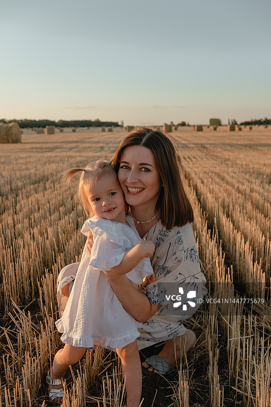 在有干草堆的田野里的母女肖像图片素材