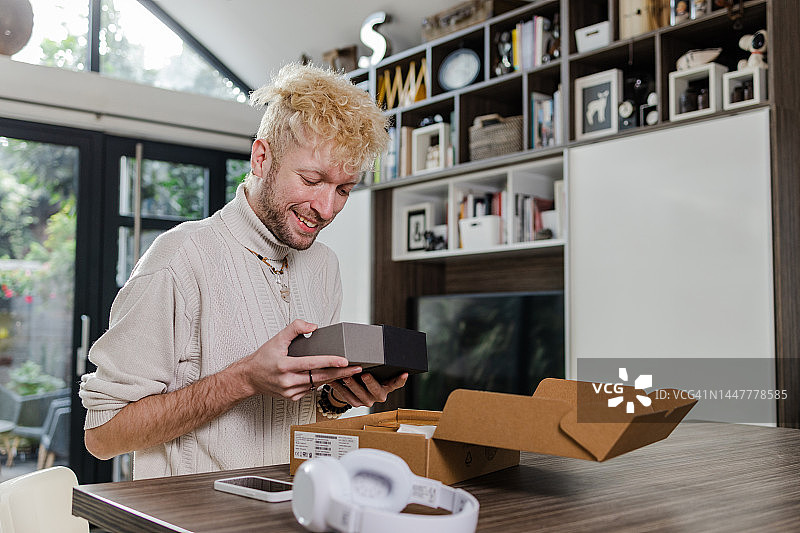 年轻男人打开快递箱并拿着产品图片素材
