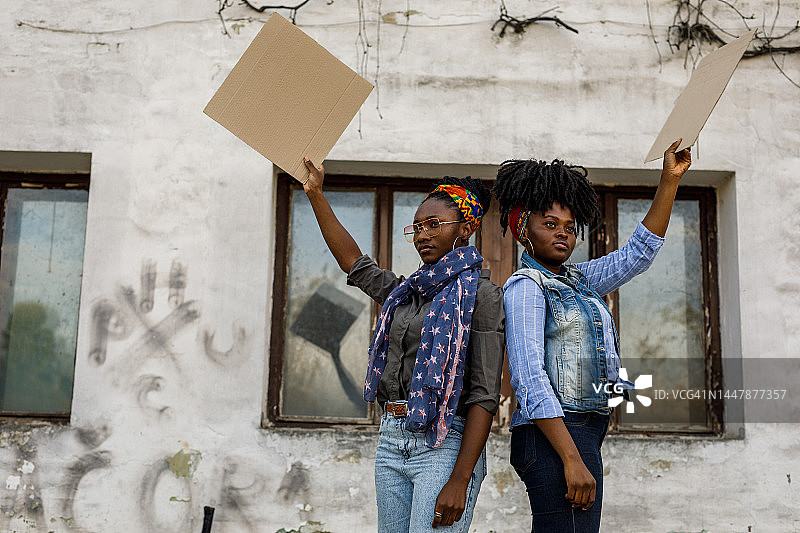 两名年轻黑人女权主义者举着纸板在城市街道上抗议图片素材