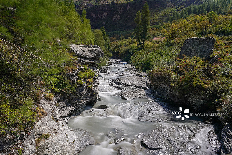 森林边缘、山脚下的河流中心图片素材