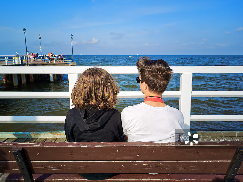 女孩和男孩坐在长椅上的背影图片素材