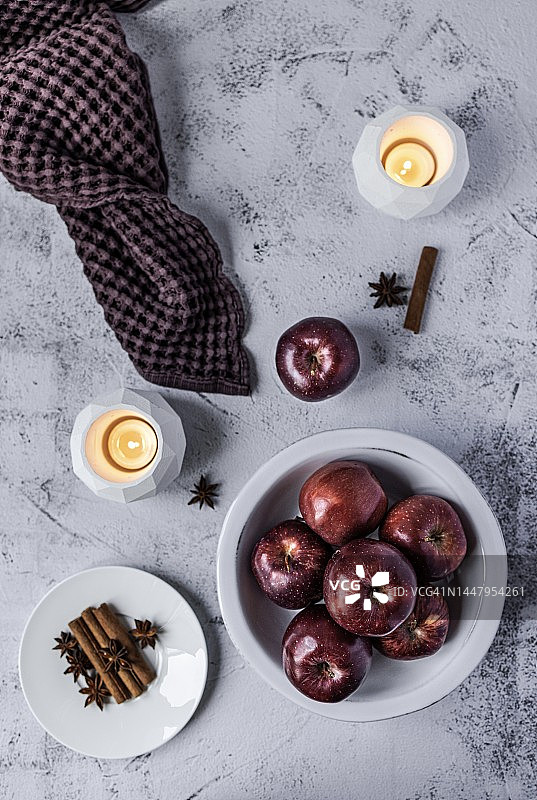 白色盘子里的红色闪亮苹果、紫色亚麻餐巾和烛台图片素材