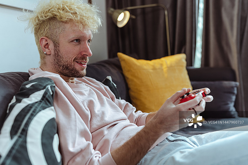 侧视照片：微笑的男人在玩电子游戏图片素材