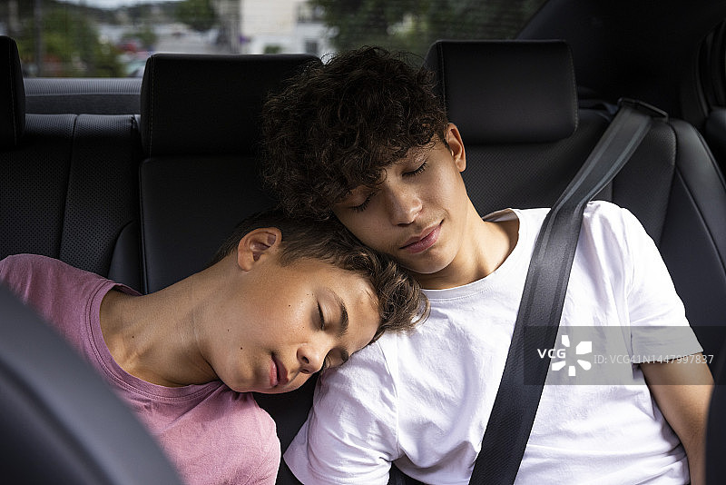 疲惫的兄弟在车里休息时互相依靠图片素材