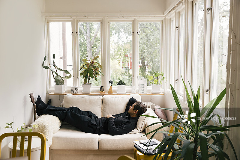 男子在家中客厅的沙发上睡觉的侧视图图片素材
