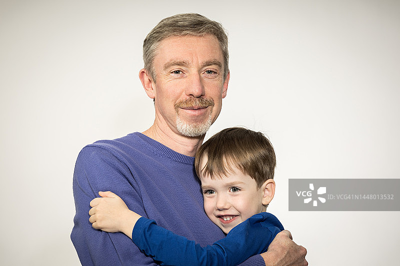 白色背景上的50岁白人男子和5岁儿子的棚拍肖像图片素材