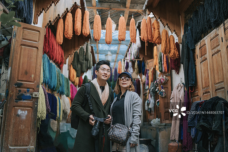 中国游客夫妇在摩洛哥菲斯露天市场的小巷里散步图片素材