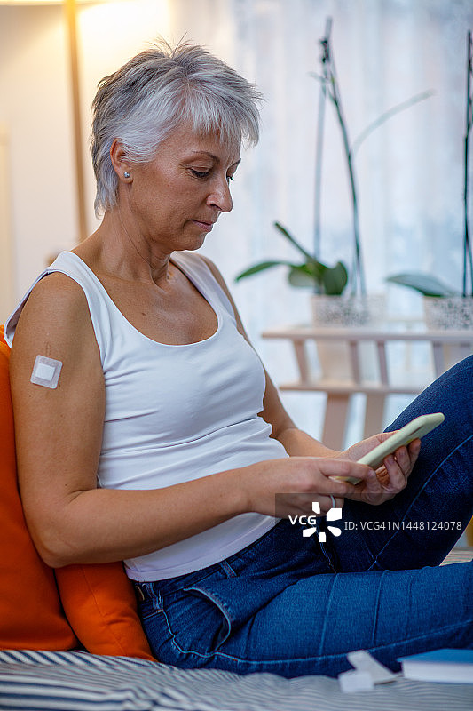 中年妇女正在放松并使用智能手机图片素材