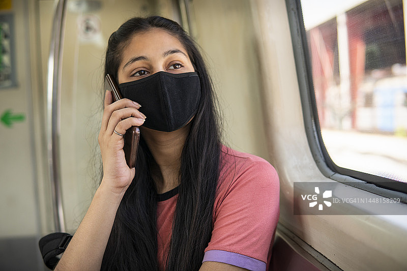 在地铁里用智能手机交谈的年轻女人图片素材