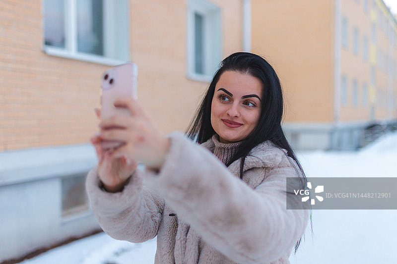 在雪地户外用视频通话的年轻女人图片素材