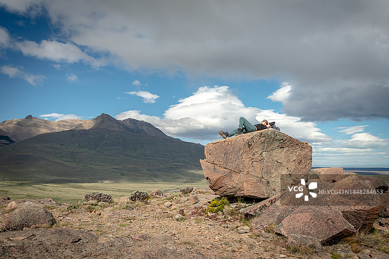 年轻的白人女性躺在去阿根廷巴塔哥尼亚查尔腾镇附近的洛斯孔多雷斯观景台和拉斯阿吉拉斯观景台的路上休息图片素材