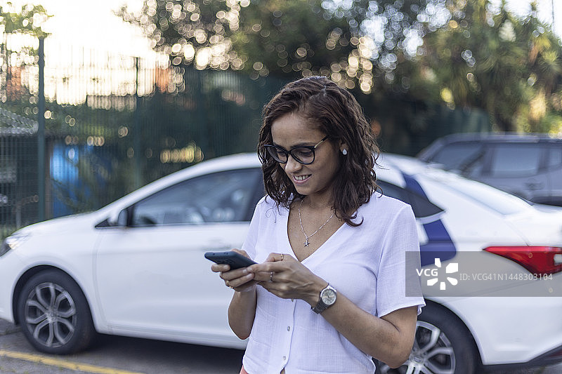在电动汽车附近使用手机的女人图片素材