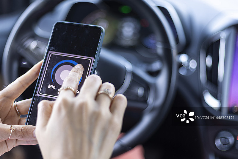 女人在电动汽车内用手机控制温度图片素材