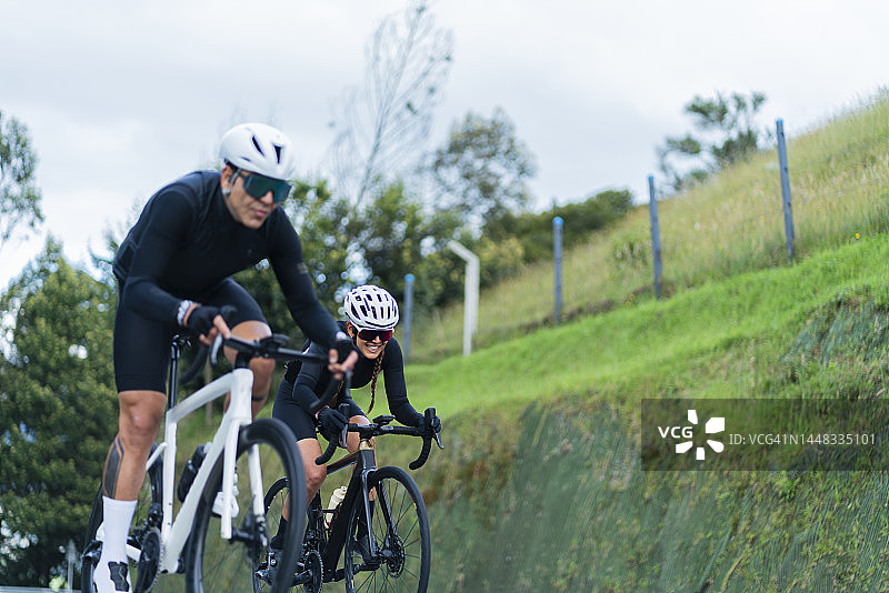 情侣骑着白色自行车在卡希卡-昆迪纳马卡路上行驶，戴着安全头盔和骑行眼镜图片素材