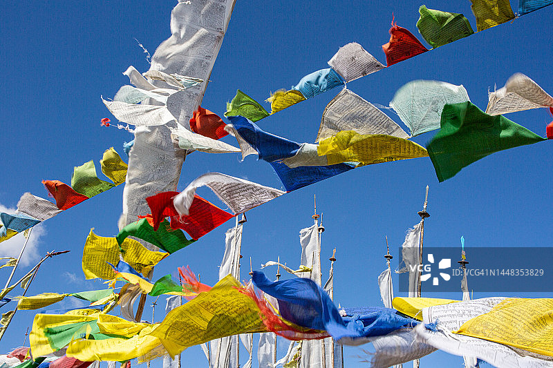 在壮丽的蓝色天空背景下，彩色佛教祈祷旗在风中飘扬的第一视角图片素材