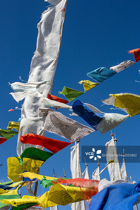 在壮丽的蓝色天空背景下，彩色佛教祈祷旗在风中飘扬的第一视角图片素材