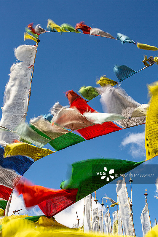 在壮丽的蓝色天空背景下，彩色佛教祈祷旗在风中飘扬的第一视角图片素材