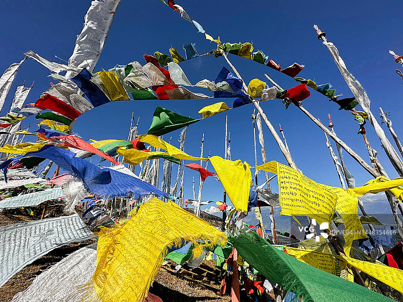 在壮丽的蓝色天空背景下，彩色佛教祈祷旗在风中飘扬的第一视角图片素材