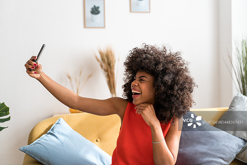 在客厅里用手机自拍的非裔发型女人图片素材